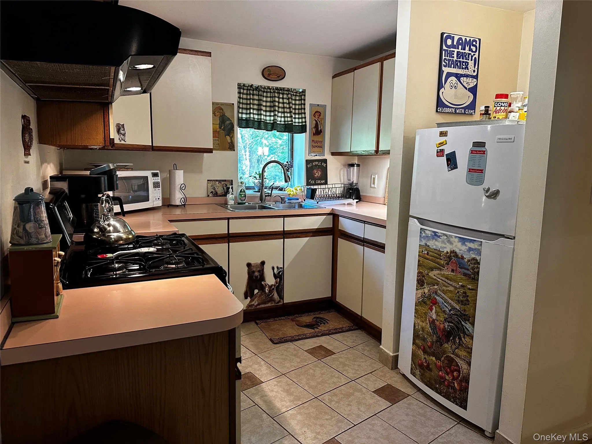 Kitchen with freestanding refrigerator, exhaust hood, light tile patterned floors, light countertops, and white cabinets Kitchen with freestanding refrigerator, exhaust hood, light tile patterned floors, light countertops, and white cabinets