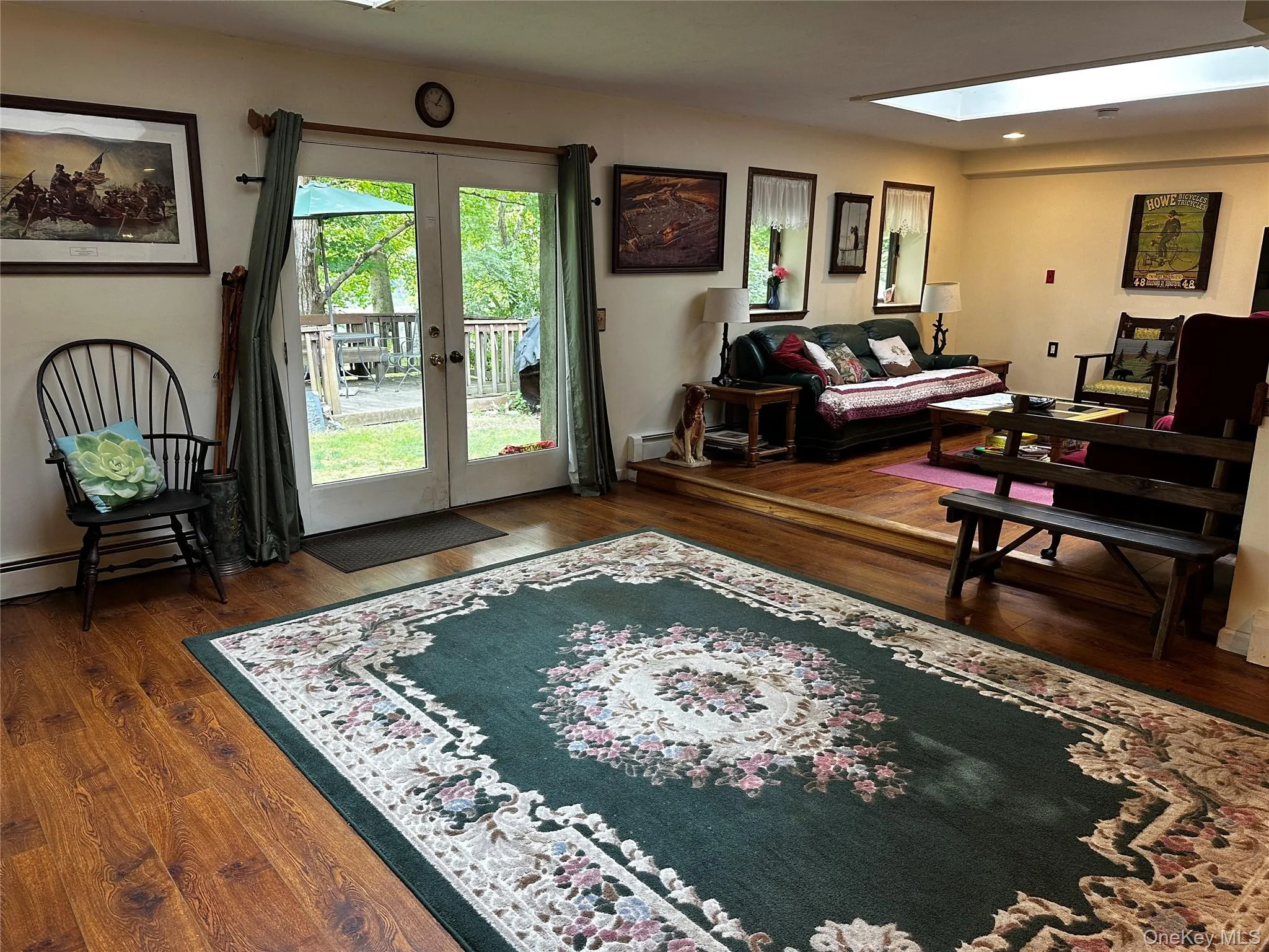 Living room featuring french doors, wood finished floors, and a skylight Living room featuring french doors, wood finished floors, and a skylight