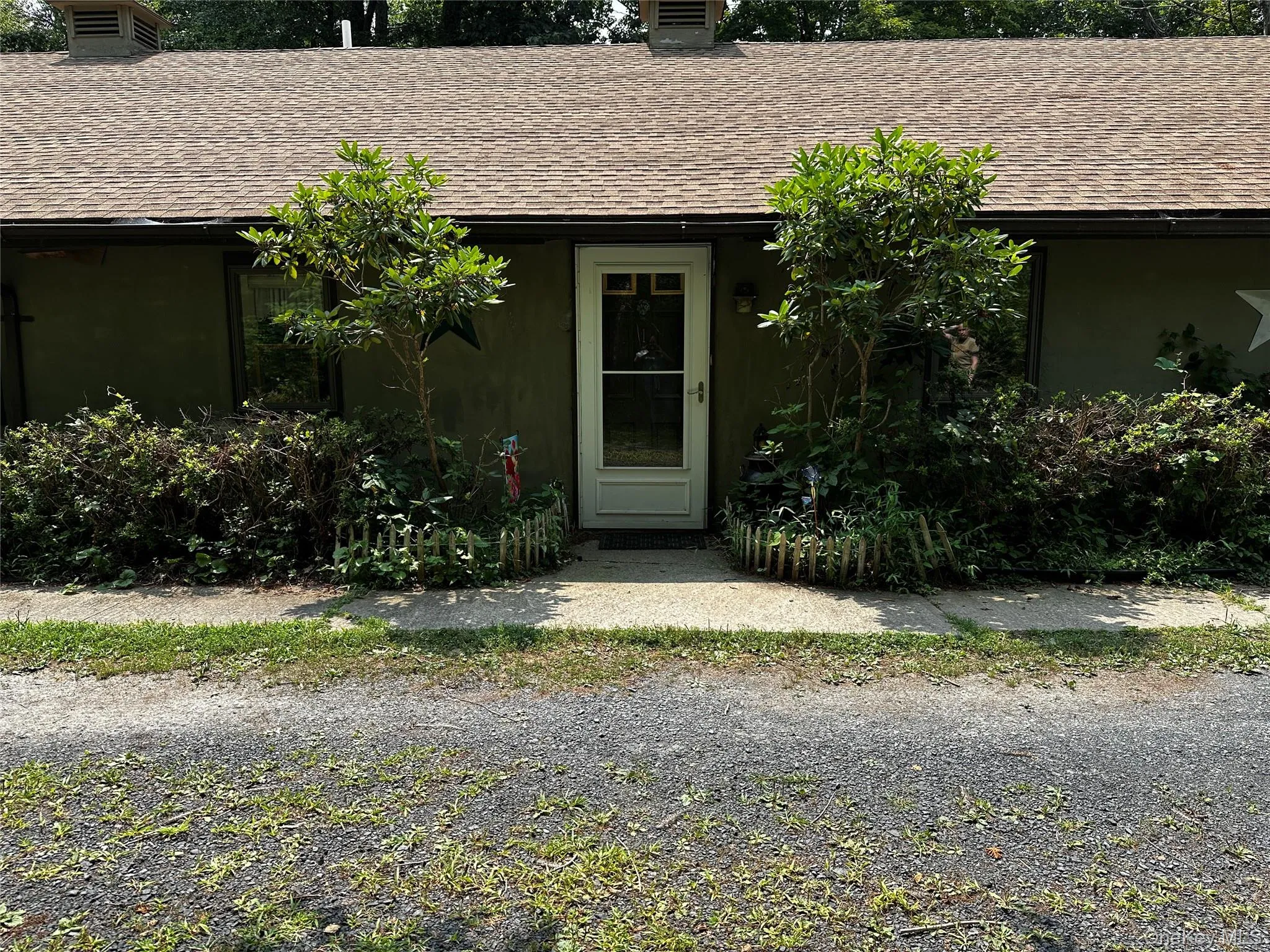 Entrance to property featuring a shingled roof and a chimney Entrance to property featuring a shingled roof and a chimney