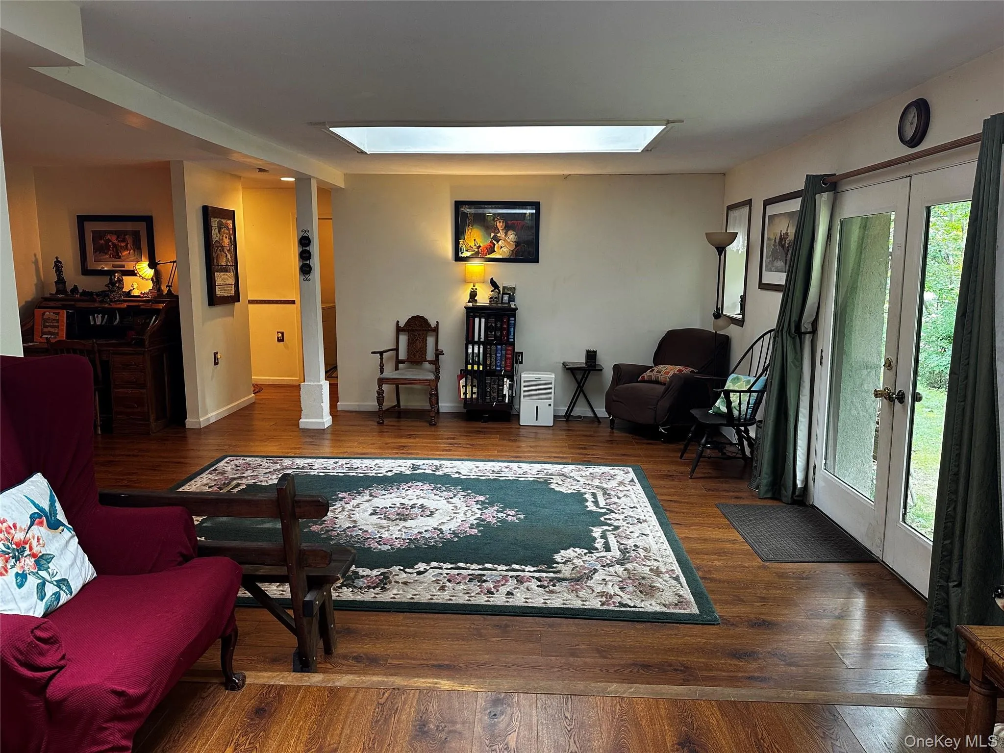 Living room featuring french doors, a skylight, and hardwood / wood-style floors Living room featuring french doors, a skylight, and hardwood / wood-style floors