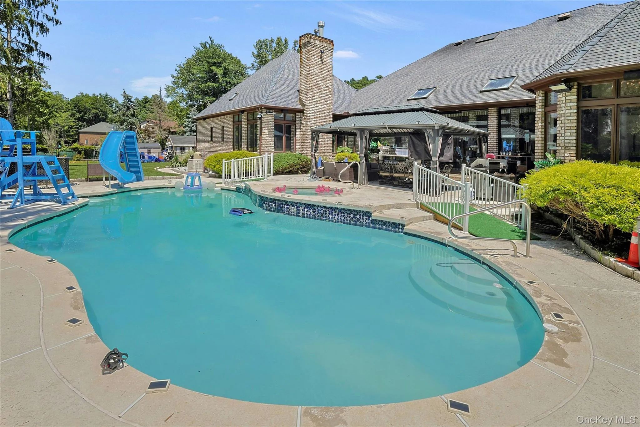 View of pool featuring a gazebo, a water slide, a patio, and an outdoor hot tub View of pool featuring a gazebo, a water slide, a patio, and an outdoor hot tub