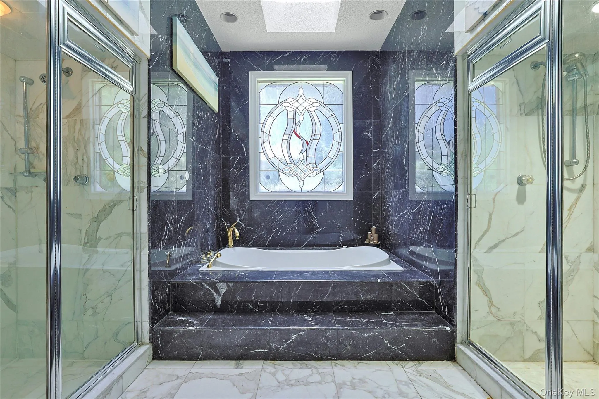 Full bathroom featuring marble tiled flooring, tile walls, a marble finish shower, and a garden tub Full bathroom featuring marble tiled flooring, tile walls, a marble finish shower, and a garden tub