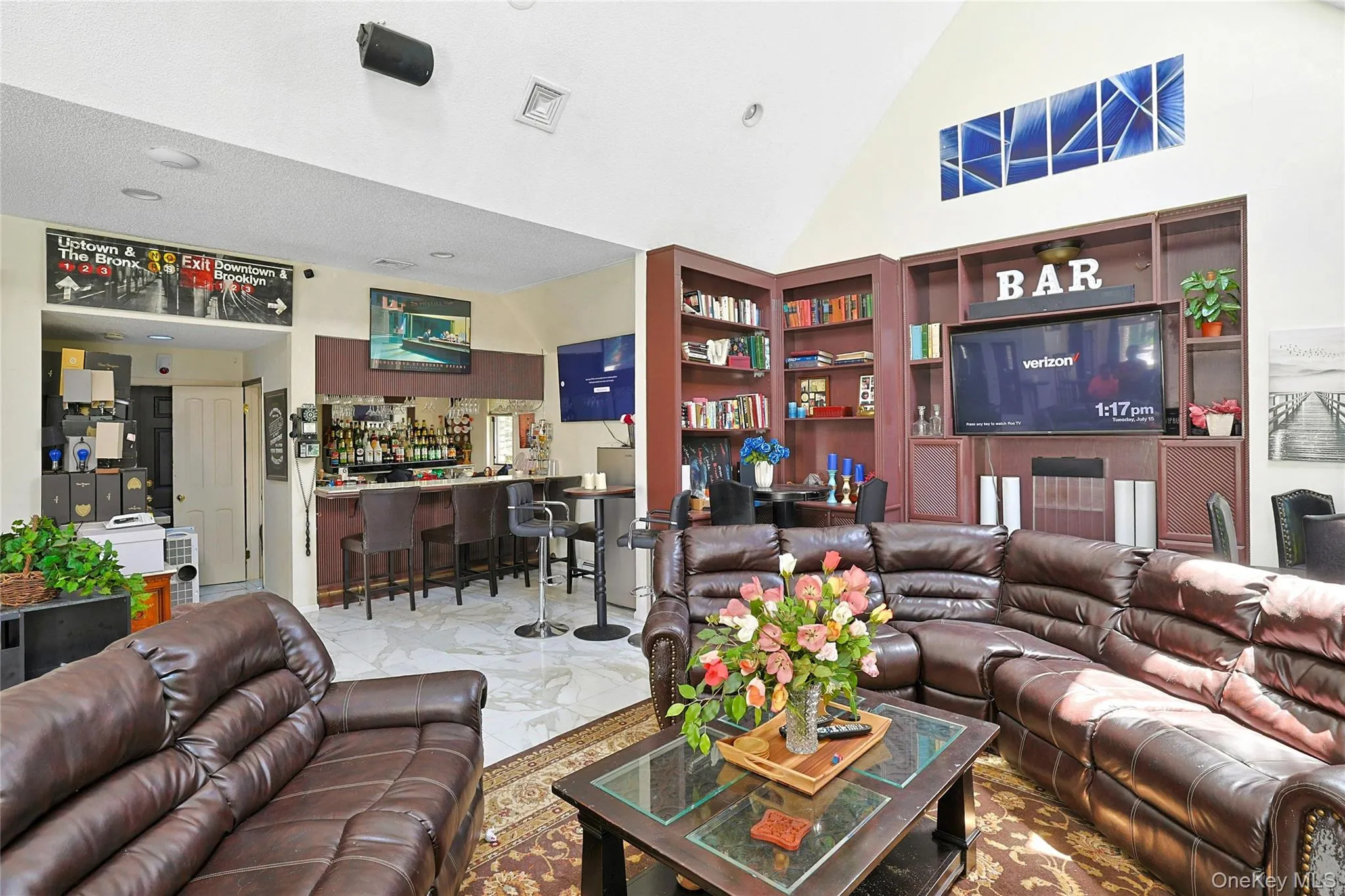 Living area with high vaulted ceiling, a dry bar, and marble look tile flooring Living area with high vaulted ceiling, a dry bar, and marble look tile flooring