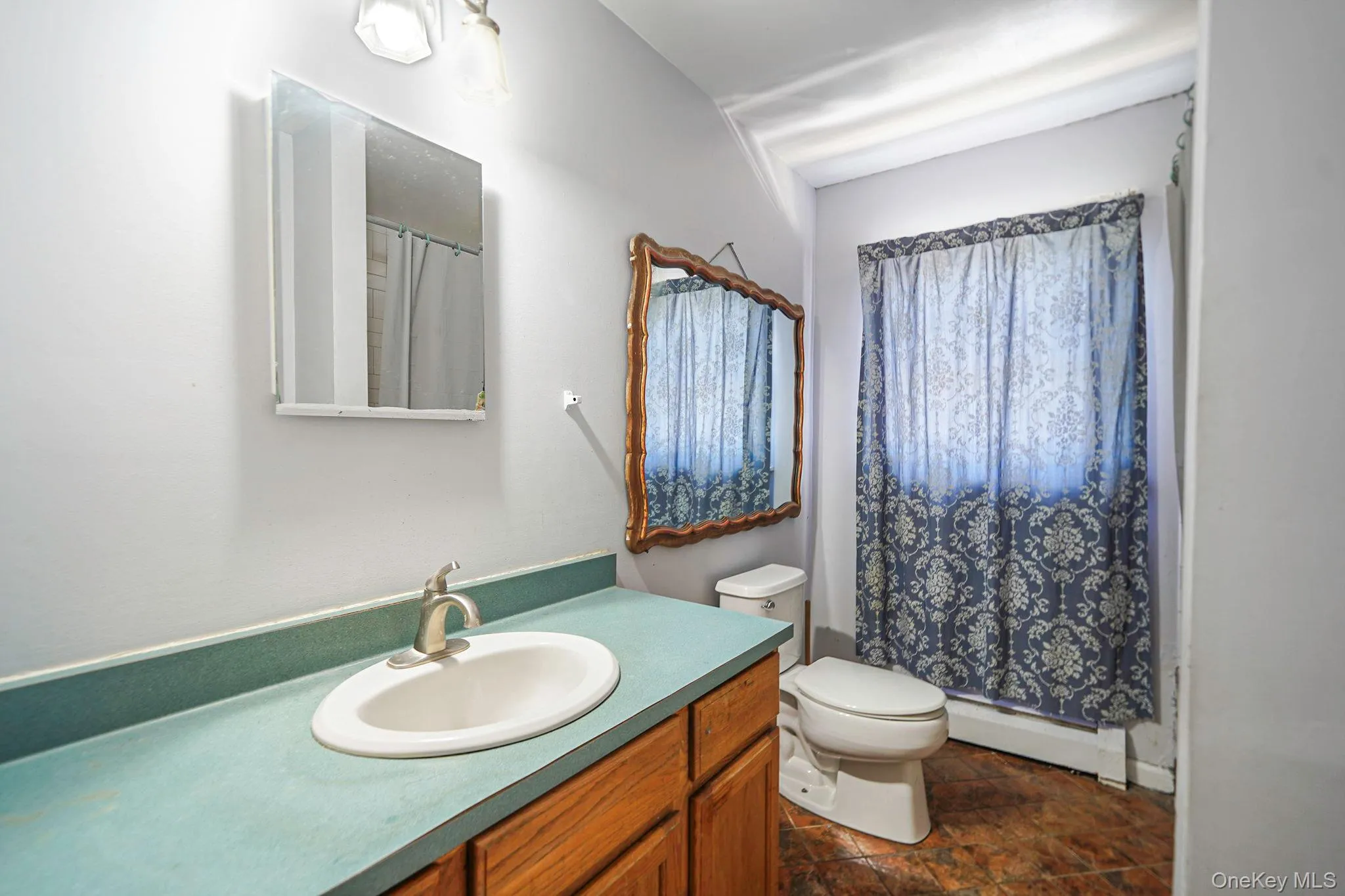 Hall Bathroom featuring a baseboard radiator, vanity, stone finish flooring, and a shower with shower curtain Hall Bathroom featuring a baseboard radiator, vanity, stone finish flooring, and a shower with shower curtain