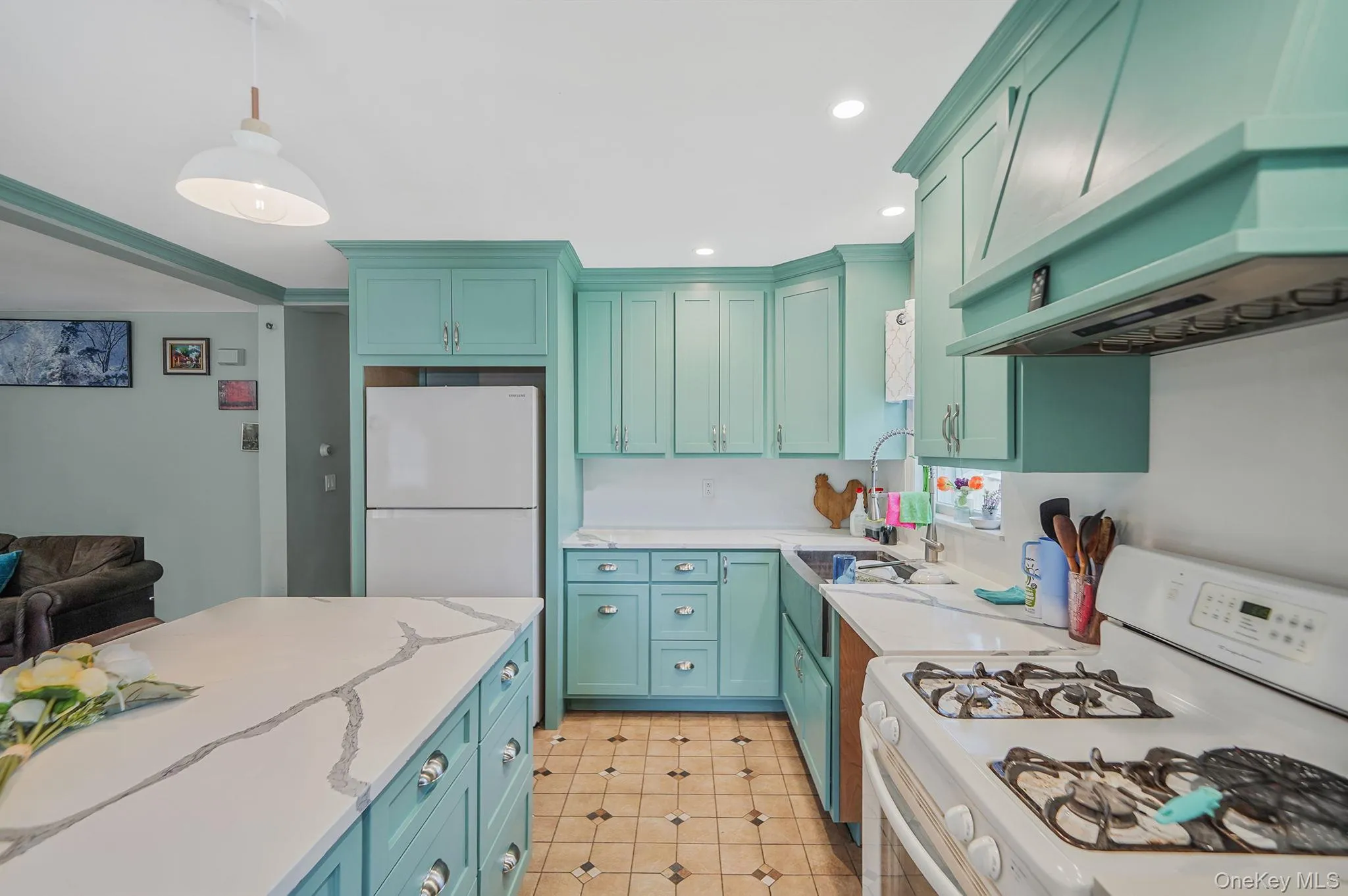Kitchen featuring white appliances, premium range hood, recessed lighting, pendant lighting, and light stone countertops Kitchen featuring white appliances, premium range hood, recessed lighting, pendant lighting, and light stone countertops