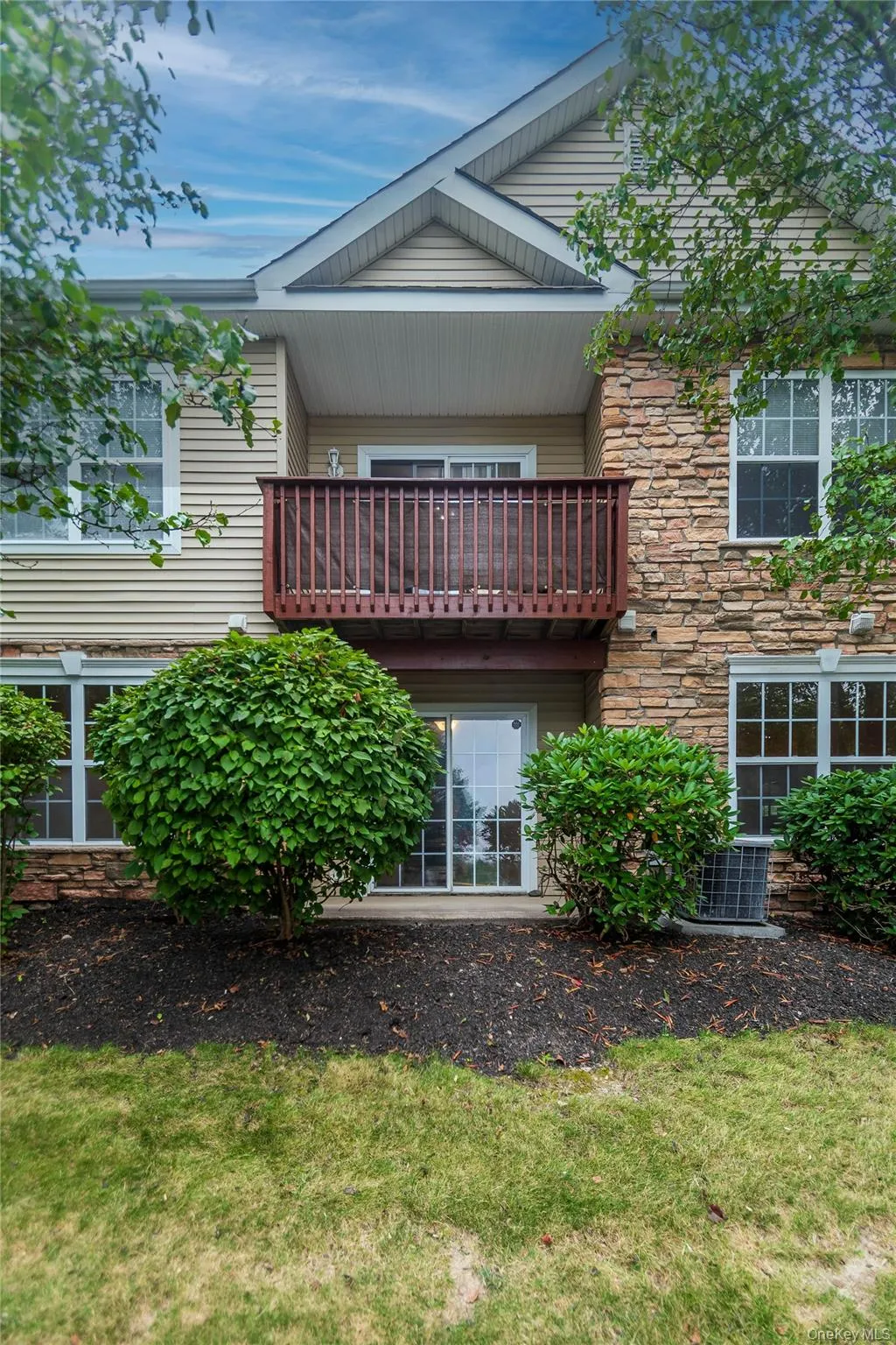 Back of property with stone siding, a balcony, and a lawn Back of property with stone siding, a balcony, and a lawn