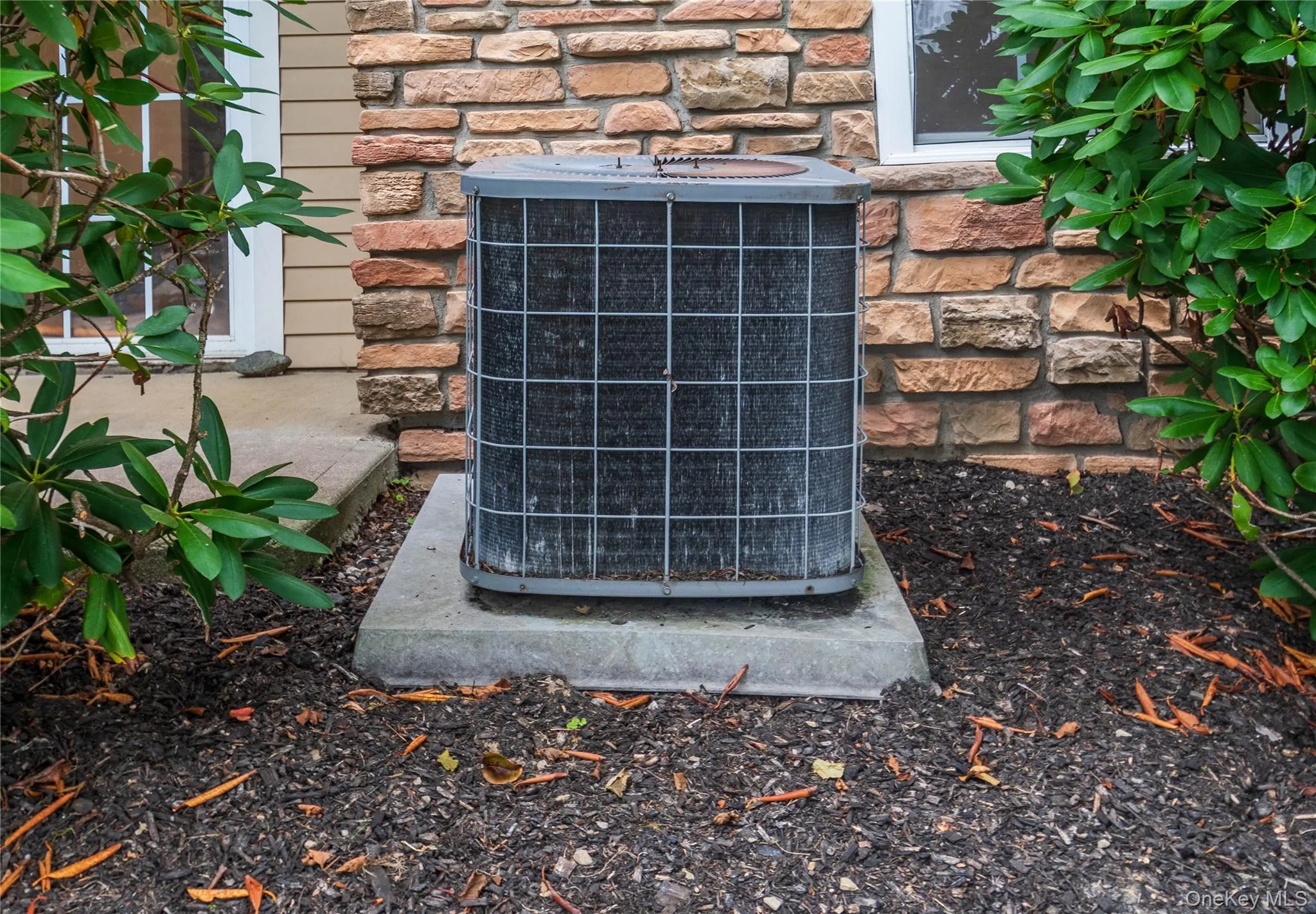 Exterior view of a cooling unit and stone siding Exterior view of a cooling unit and stone siding