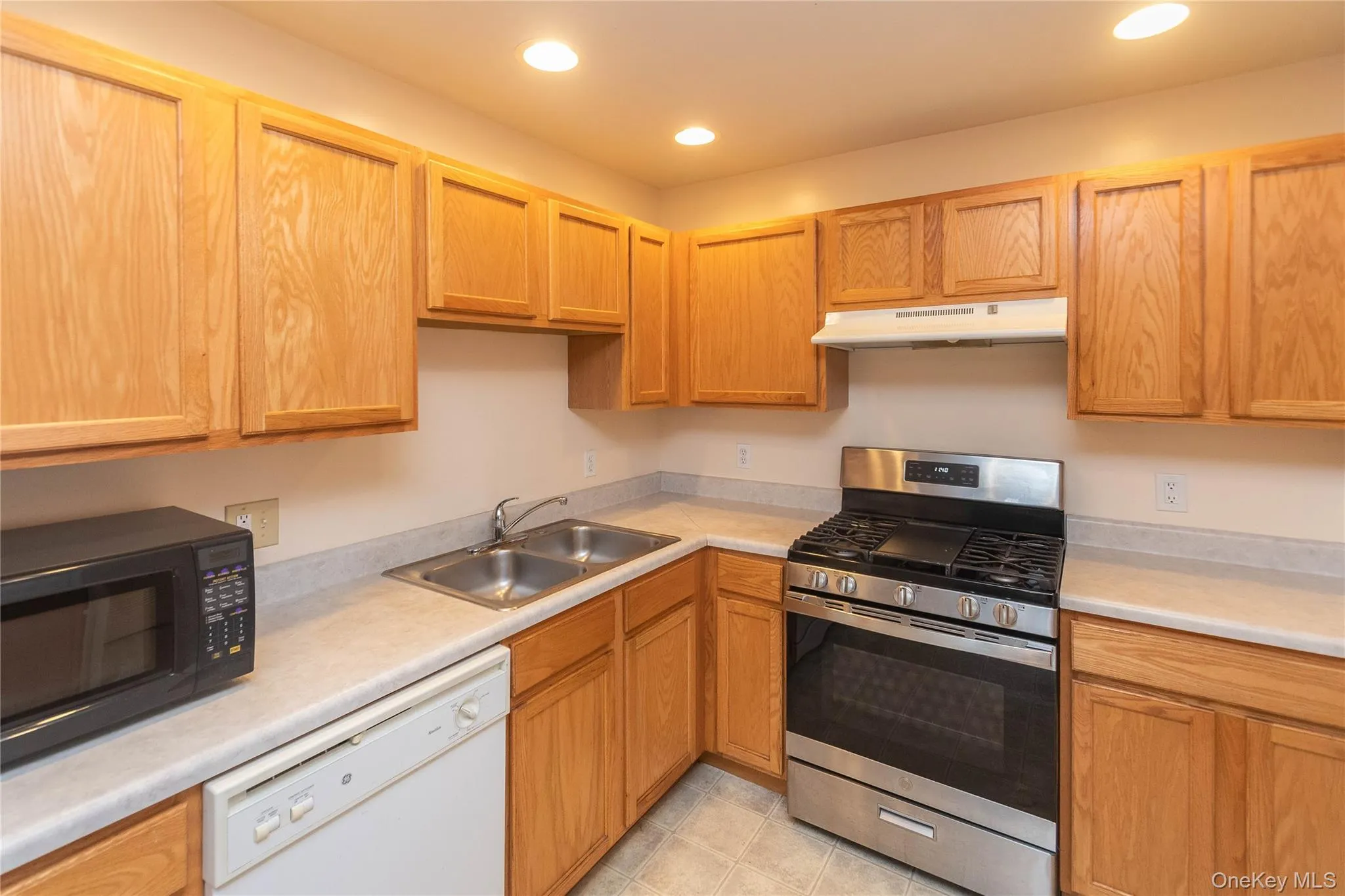 Kitchen featuring stainless steel gas range, black microwave, dishwasher, light countertops, and recessed lighting Kitchen featuring stainless steel gas range, black microwave, dishwasher, light countertops, and recessed lighting