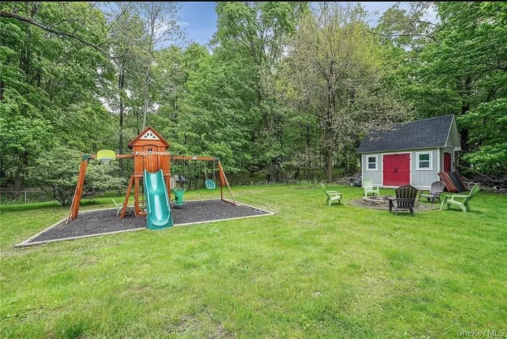 View of grassy yard with an outdoor fire pit, a playground, view of scattered trees, and a shed View of grassy yard with an outdoor fire pit, a playground, view of scattered trees, and a shed