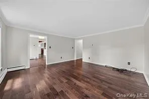 Unfurnished living room featuring crown molding and wood finished floors Unfurnished living room featuring crown molding and wood finished floors
