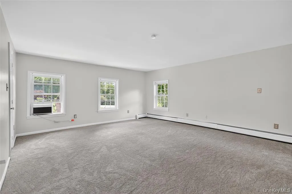 Unfurnished room with a baseboard heating unit and carpet flooring Unfurnished room with a baseboard heating unit and carpet flooring