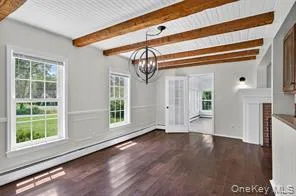 Unfurnished dining area featuring baseboard heating, a chandelier, wood finished floors, and beam ceiling Unfurnished dining area featuring baseboard heating, a chandelier, wood finished floors, and beam ceiling