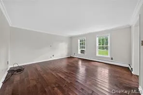 Unfurnished living room featuring wood finished floors and ornamental molding Unfurnished living room featuring wood finished floors and ornamental molding