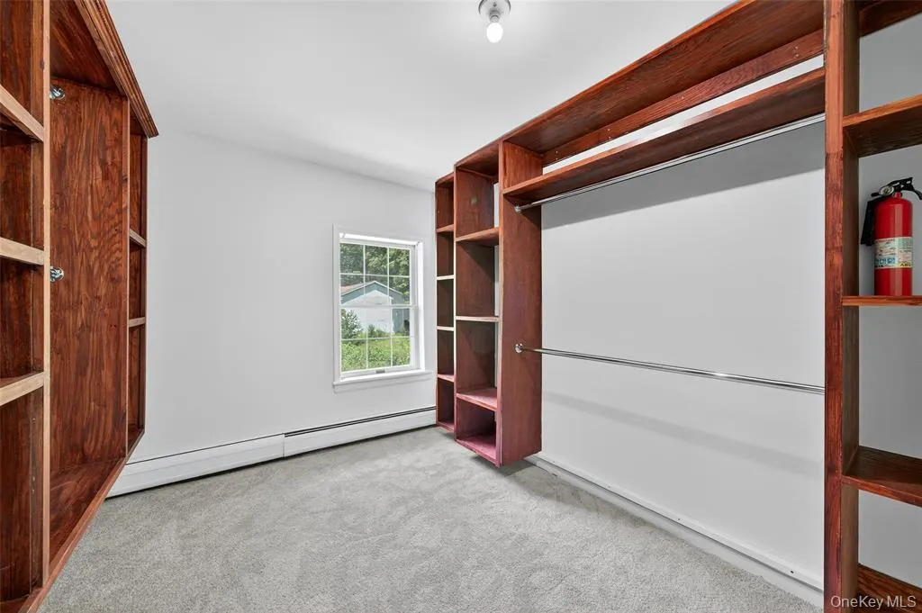 Spacious closet featuring carpet floors and a baseboard radiator Spacious closet featuring carpet floors and a baseboard radiator