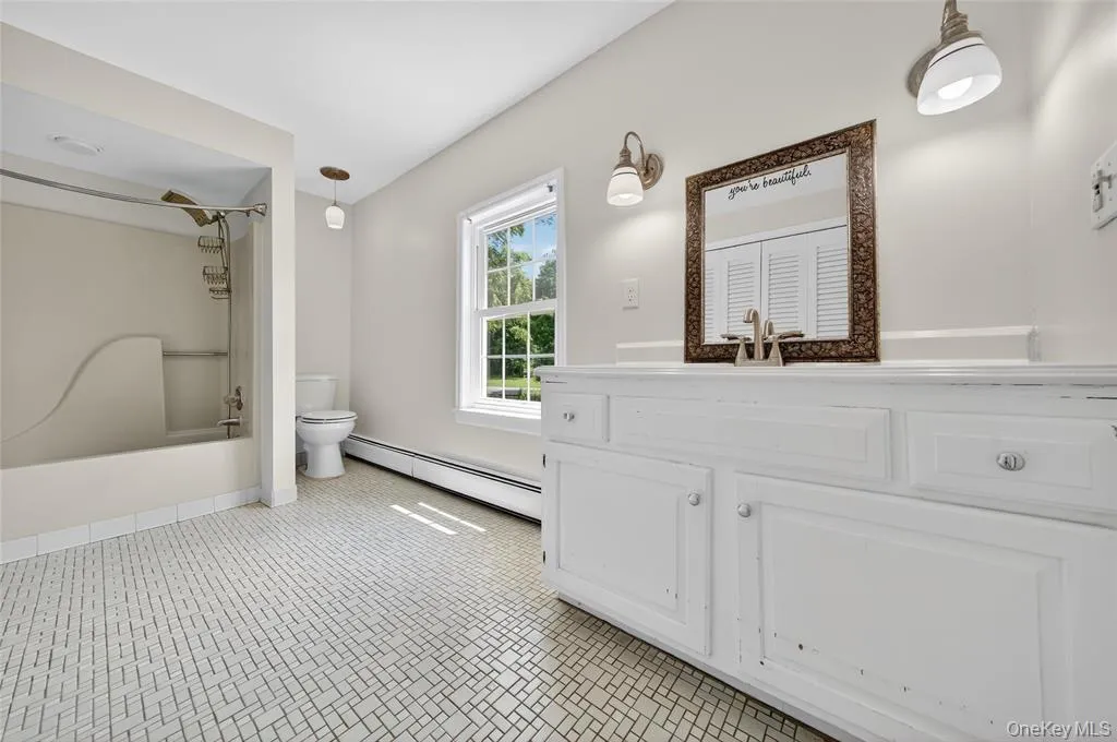 Bathroom with a baseboard radiator, washtub / shower combination, and vanity Bathroom with a baseboard radiator, washtub / shower combination, and vanity