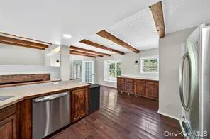Kitchen with beam ceiling, stainless steel appliances, dark wood-style floors, and light countertops Kitchen with beam ceiling, stainless steel appliances, dark wood-style floors, and light countertops