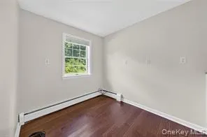 Spare room featuring wood finished floors and a baseboard radiator Spare room featuring wood finished floors and a baseboard radiator