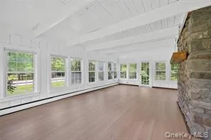 Unfurnished sunroom featuring a baseboard radiator, wood finished floors, and beamed ceiling Unfurnished sunroom featuring a baseboard radiator, wood finished floors, and beamed ceiling