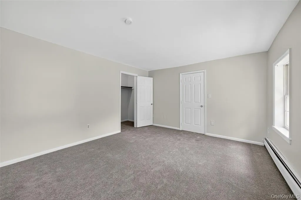 Unfurnished bedroom with a baseboard heating unit, carpet flooring, and a closet Unfurnished bedroom with a baseboard heating unit, carpet flooring, and a closet