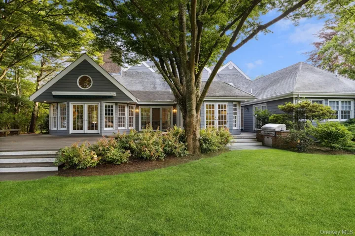 Rear view of house with a deck, french doors, a chimney, and a lawn