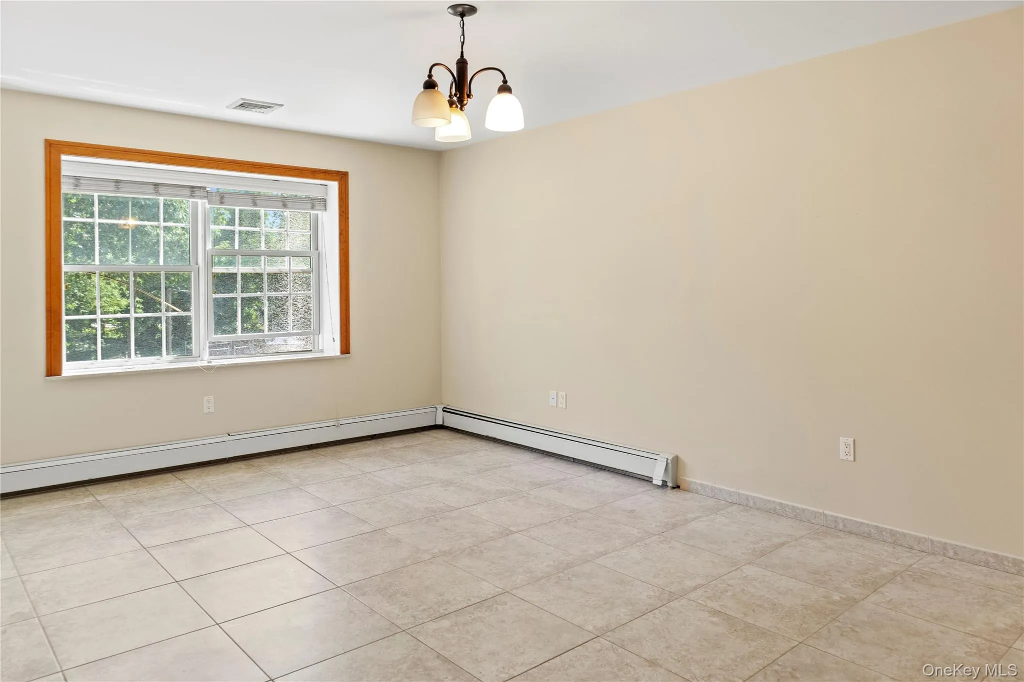 Spare room featuring a chandelier, a baseboard radiator, and light tile patterned floors Spare room featuring a chandelier, a baseboard radiator, and light tile patterned floors