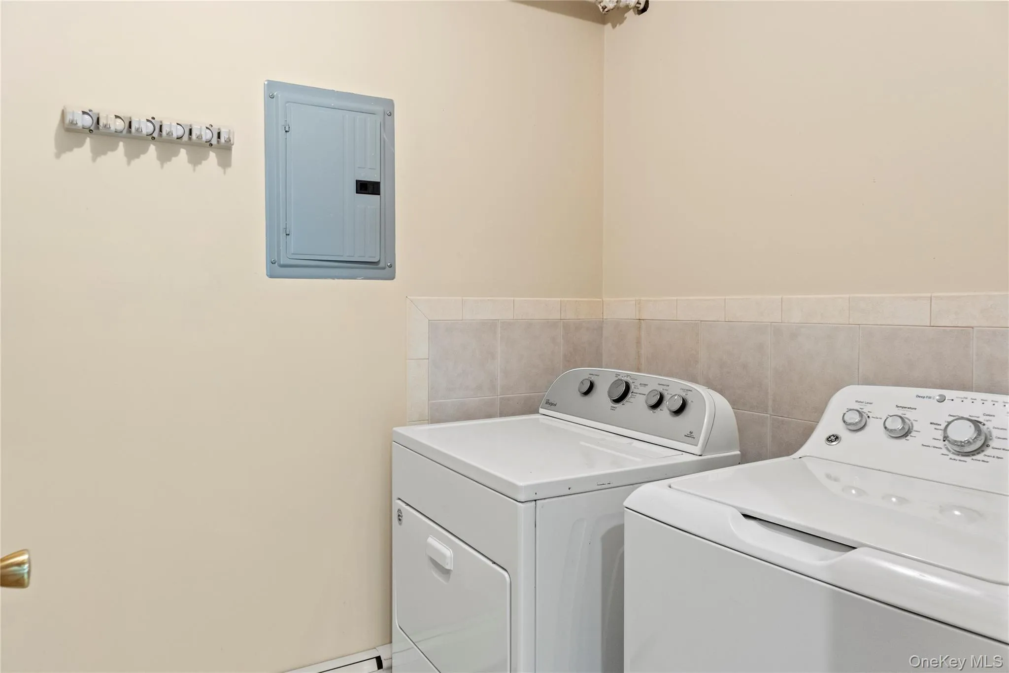 Laundry area featuring washer and clothes dryer, electric panel, and tile walls Laundry area featuring washer and clothes dryer, electric panel, and tile walls