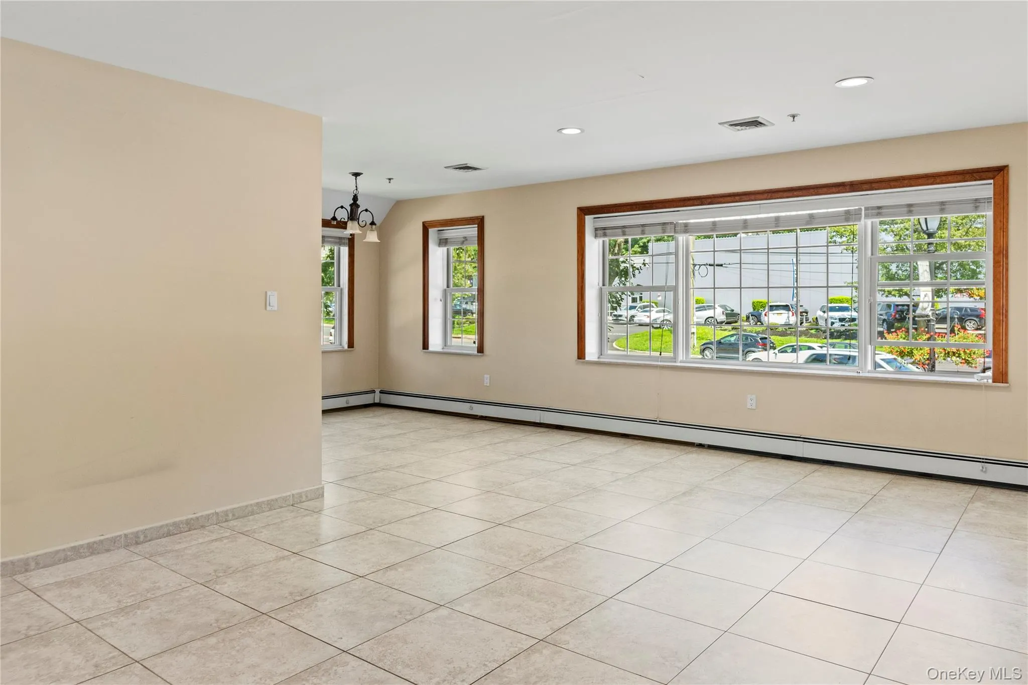 Spare room featuring light tile patterned flooring, a baseboard radiator, recessed lighting, and a chandelier Spare room featuring light tile patterned flooring, a baseboard radiator, recessed lighting, and a chandelier