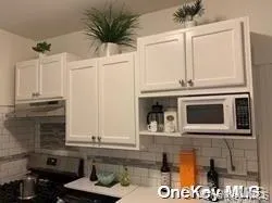 Kitchen with stainless steel electric range, white microwave, decorative backsplash, under cabinet range hood, and white cabinetry Kitchen with stainless steel electric range, white microwave, decorative backsplash, under cabinet range hood, and white cabinetry