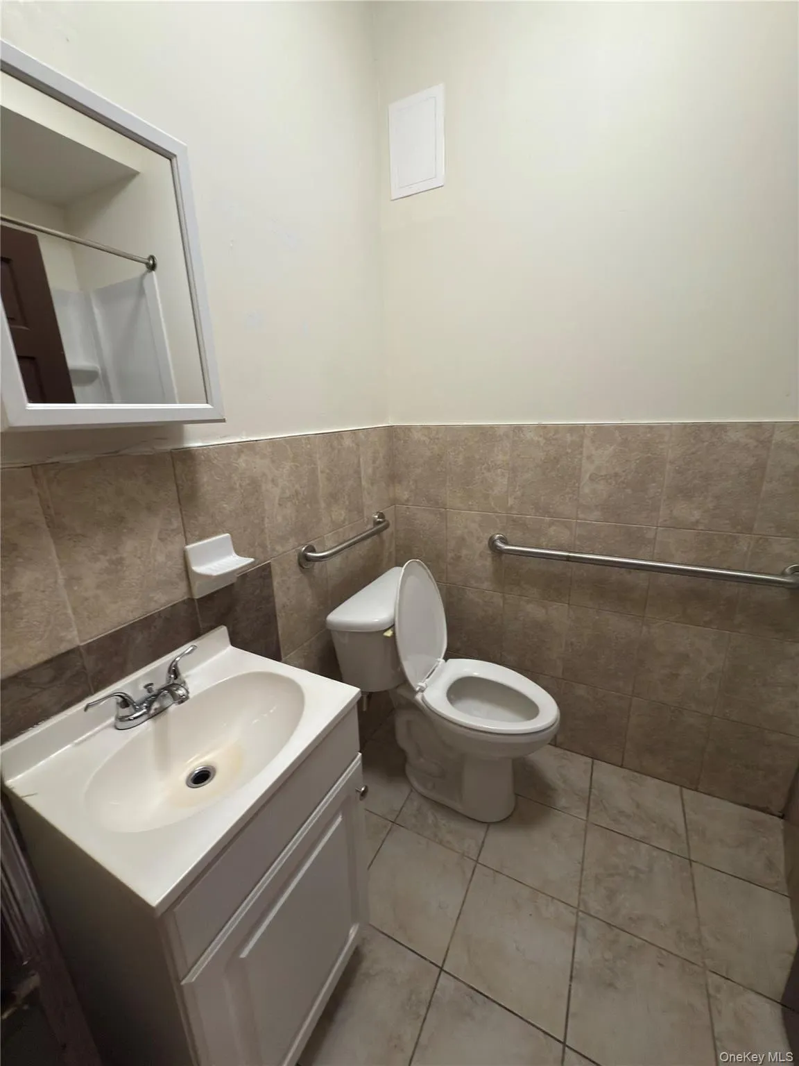 Bathroom with vanity, tile patterned flooring, tile walls, and wainscoting Bathroom with vanity, tile patterned flooring, tile walls, and wainscoting