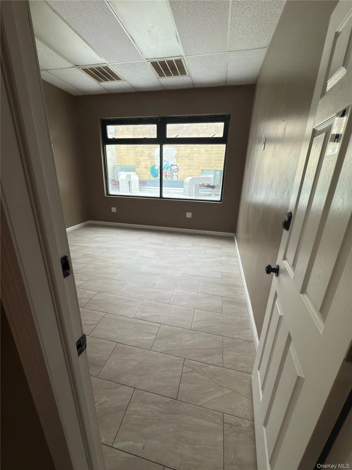Empty room with a drop ceiling and baseboards Empty room with a drop ceiling and baseboards