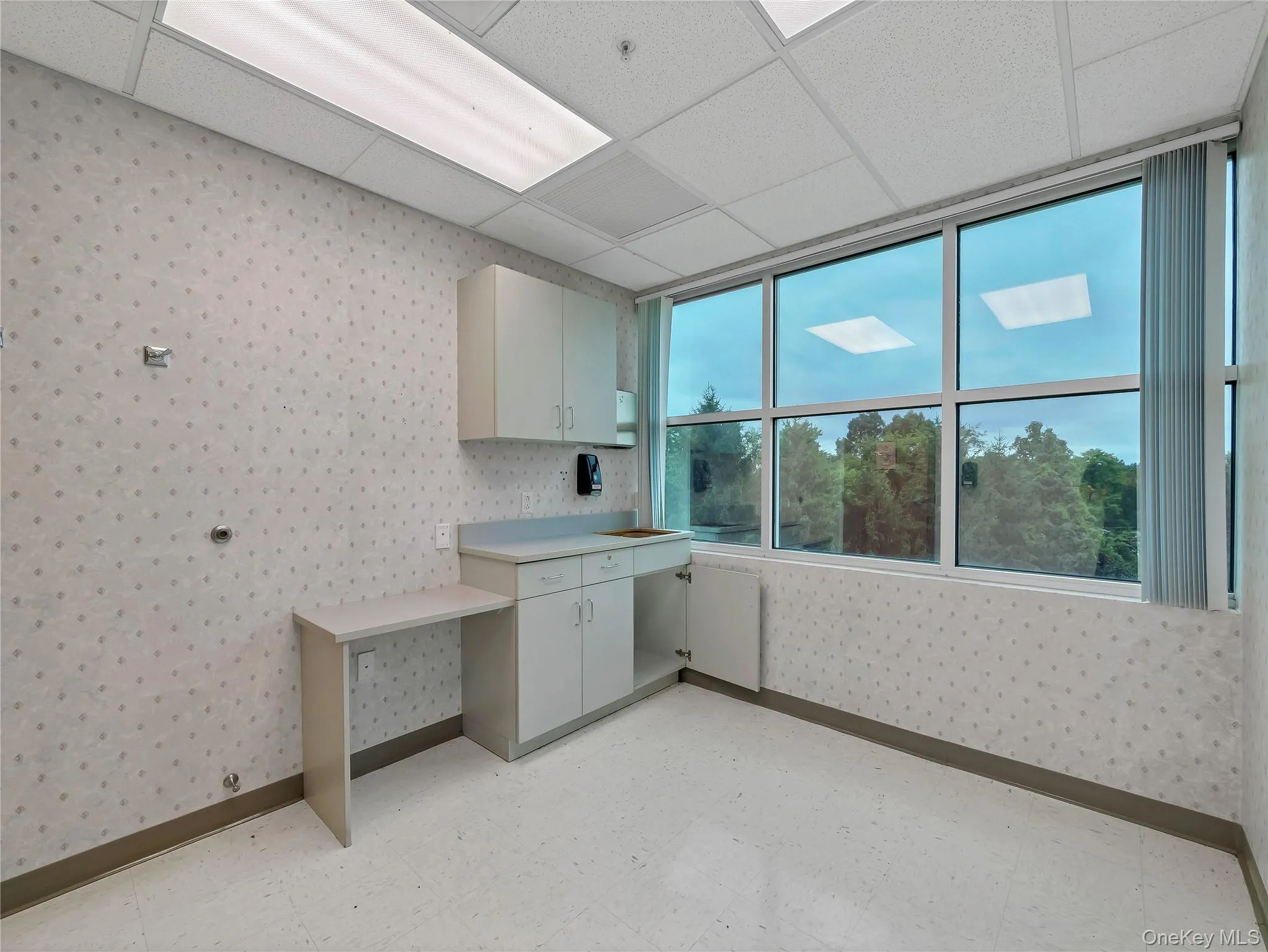 Laundry area featuring wallpapered walls and baseboards Laundry area featuring wallpapered walls and baseboards