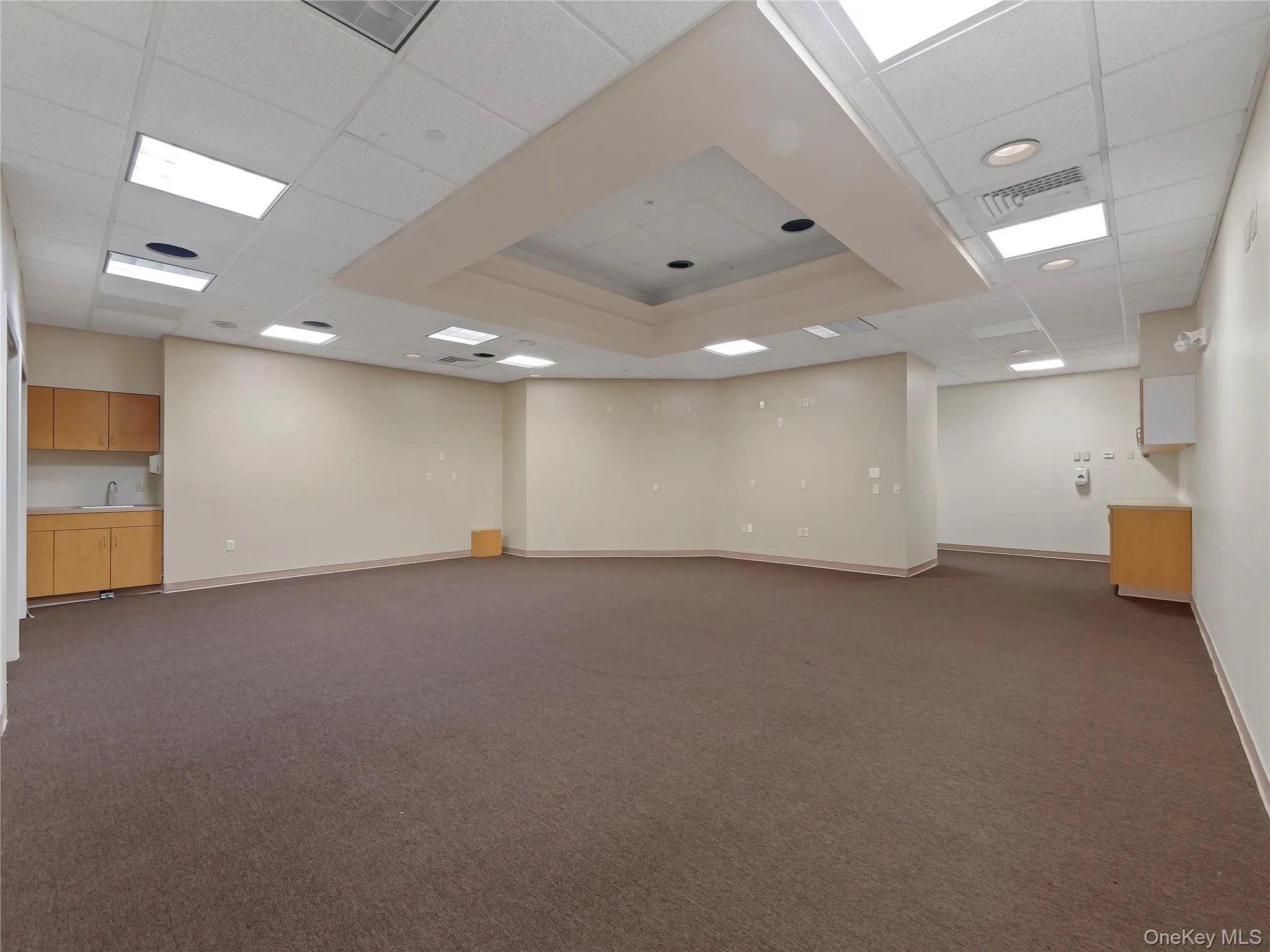 Basement with a drop ceiling and dark colored carpet Basement with a drop ceiling and dark colored carpet