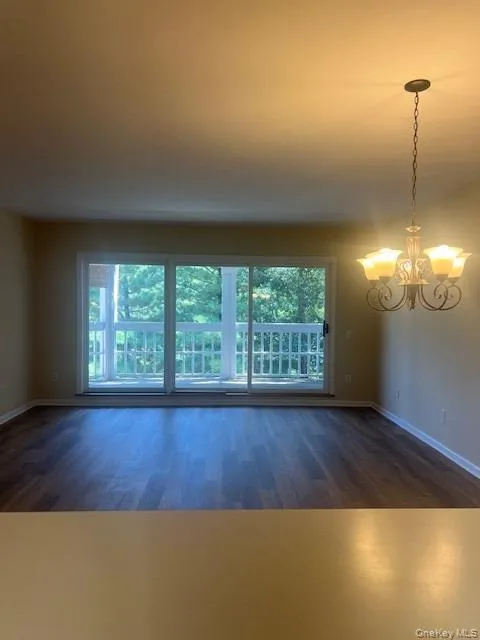 Spare room with dark wood finished floors and a chandelier Spare room with dark wood finished floors and a chandelier