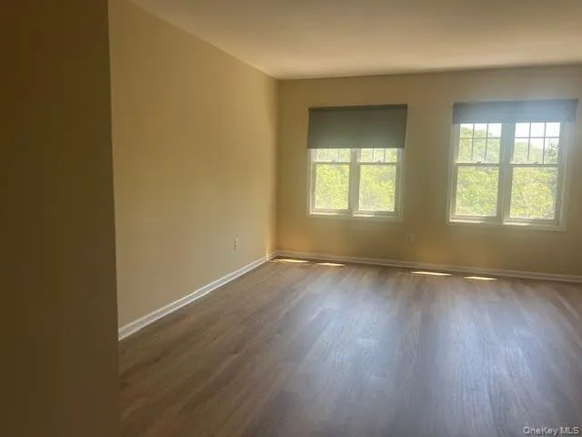 Unfurnished room with dark wood-style flooring and baseboards Unfurnished room with dark wood-style flooring and baseboards