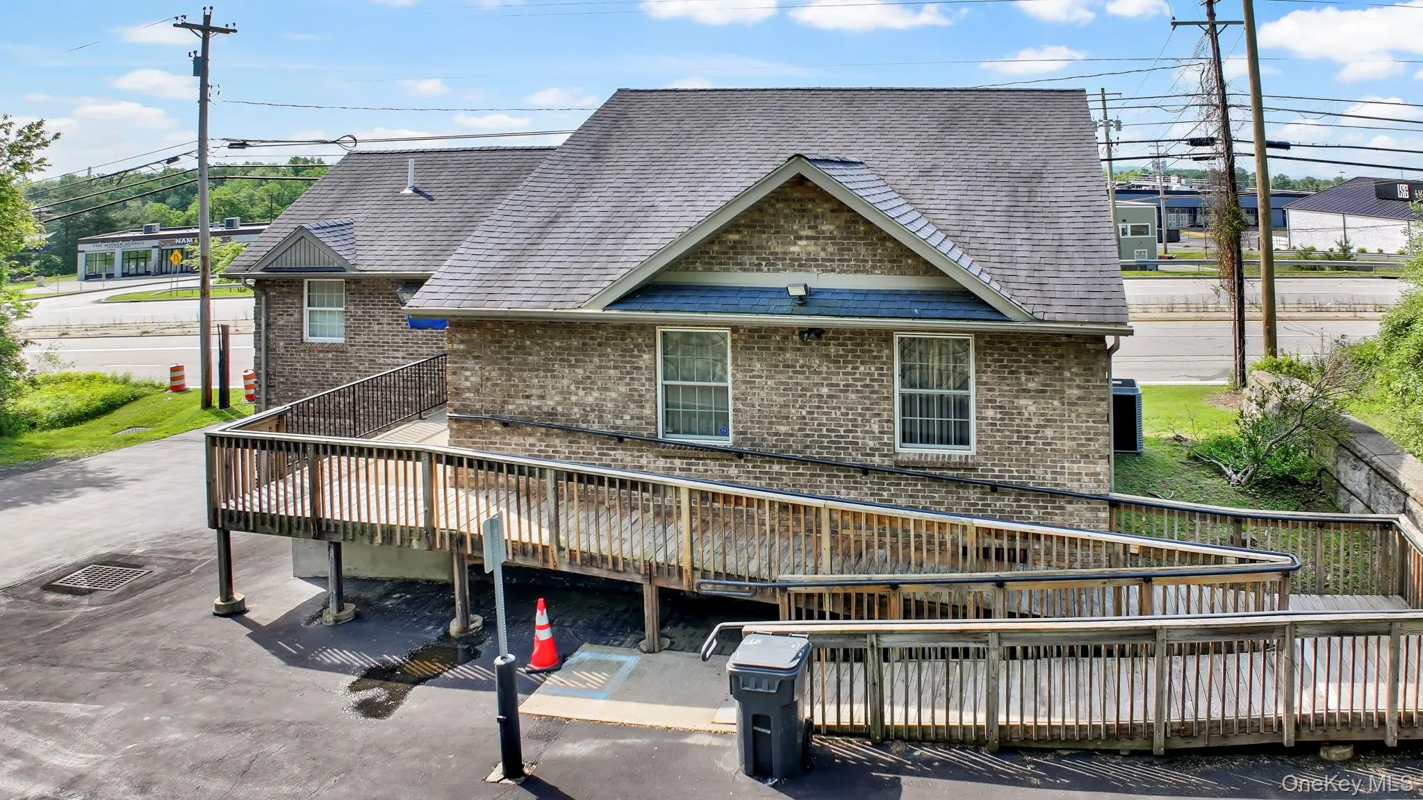 Back of property featuring brick siding, a wooden deck, and roof with shingles Back of property featuring brick siding, a wooden deck, and roof with shingles