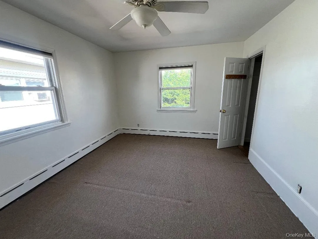 Spare room with a baseboard radiator, carpet, and a ceiling fan Spare room with a baseboard radiator, carpet, and a ceiling fan