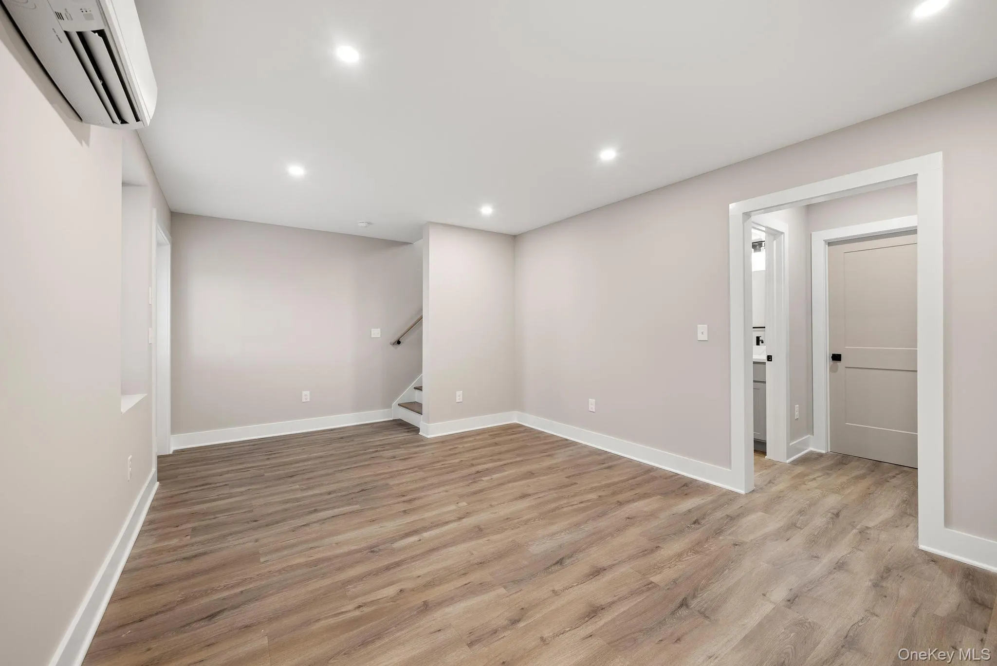 Basement featuring light wood-type flooring, a wall mounted air conditioner, recessed lighting, and stairway Basement featuring light wood-type flooring, a wall mounted air conditioner, recessed lighting, and stairway