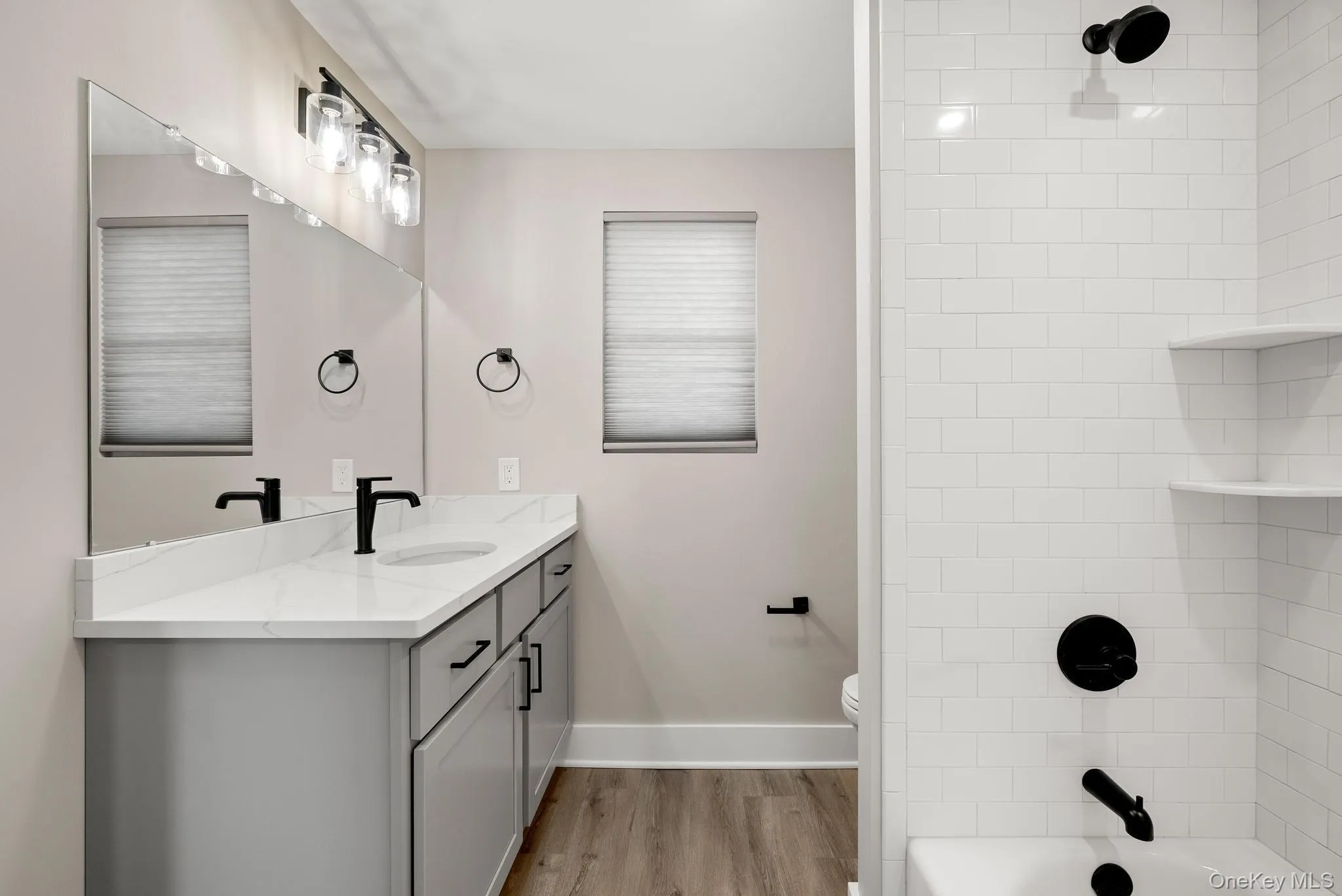 Bathroom featuring vanity, wood finished floors, and bathtub / shower combination Bathroom featuring vanity, wood finished floors, and bathtub / shower combination
