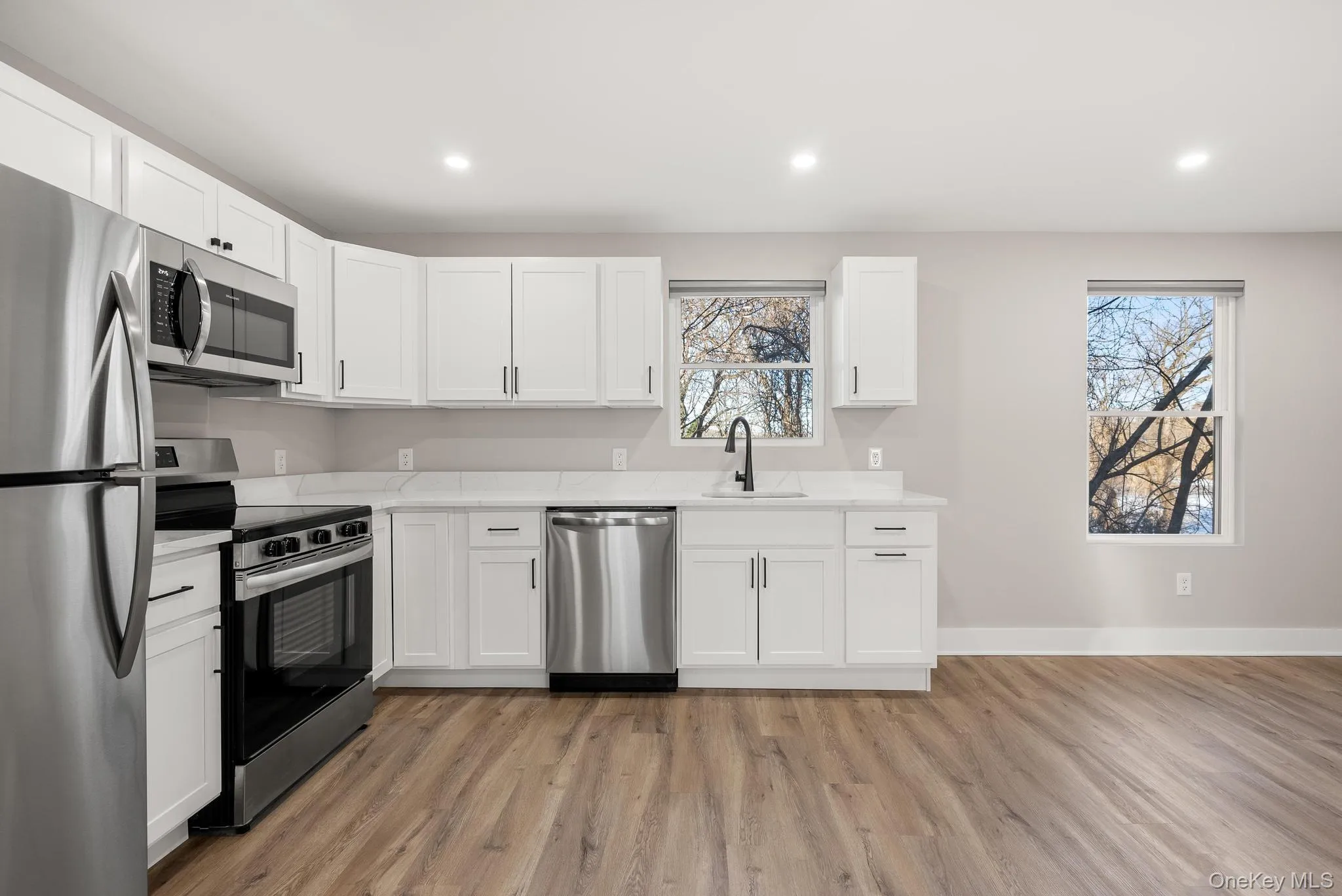 Kitchen featuring stainless steel appliances, light wood-style flooring, recessed lighting, and white cabinetry Kitchen featuring stainless steel appliances, light wood-style flooring, recessed lighting, and white cabinetry