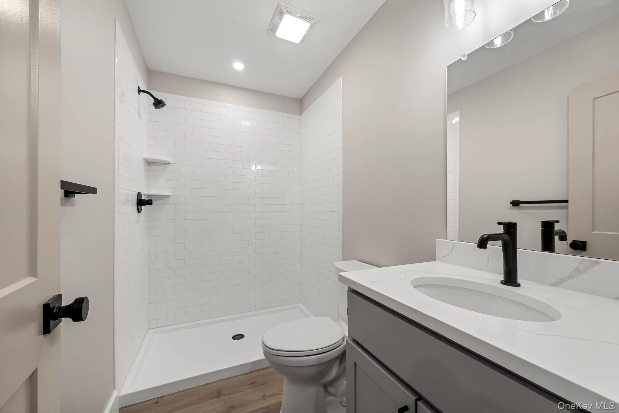 Bathroom with vanity, wood finished floors, a tile shower, and recessed lighting Bathroom with vanity, wood finished floors, a tile shower, and recessed lighting