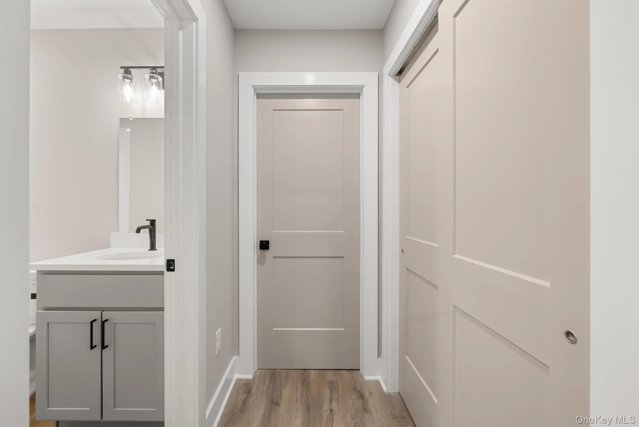 Hallway featuring light wood finished floors and a sink Hallway featuring light wood finished floors and a sink