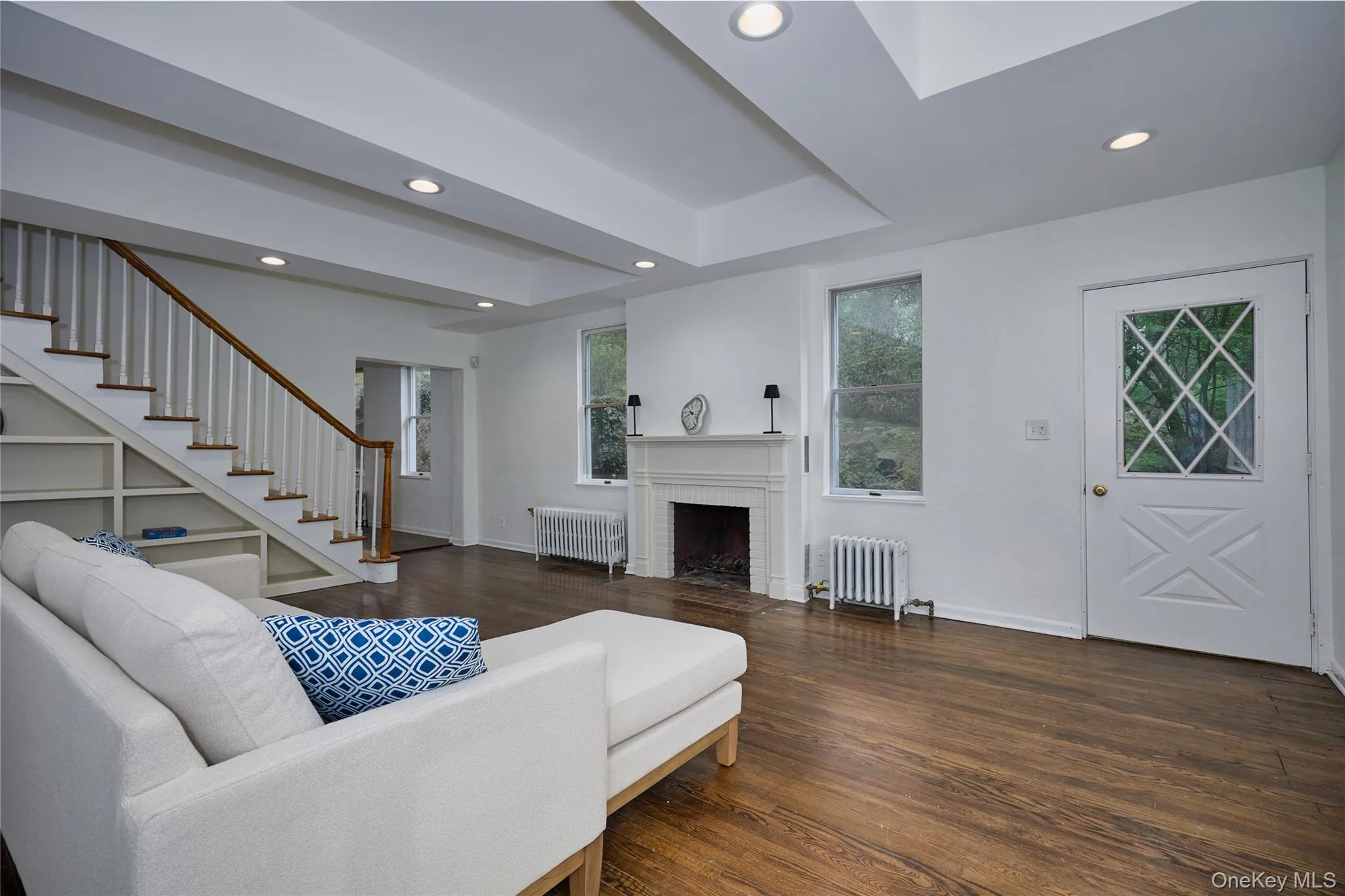 Living area with dark wood-type flooring, radiator, a brick fireplace, and recessed lighting Living area with dark wood-type flooring, radiator, a brick fireplace, and recessed lighting