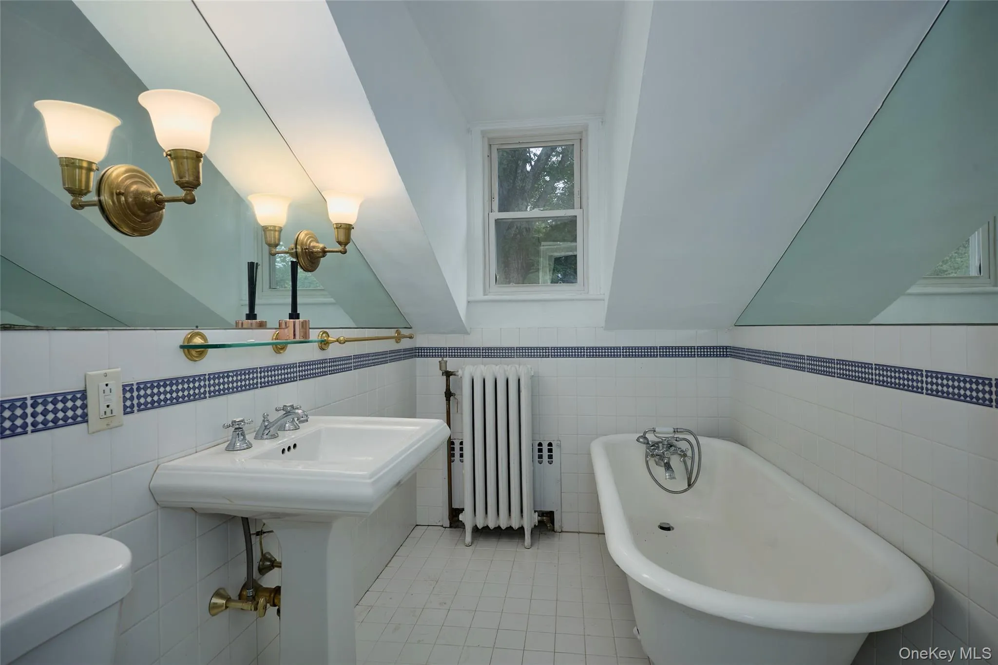 Full bath featuring lofted ceiling, a freestanding bath, radiator heating unit, tile walls, and light tile patterned floors Full bath featuring lofted ceiling, a freestanding bath, radiator heating unit, tile walls, and light tile patterned floors