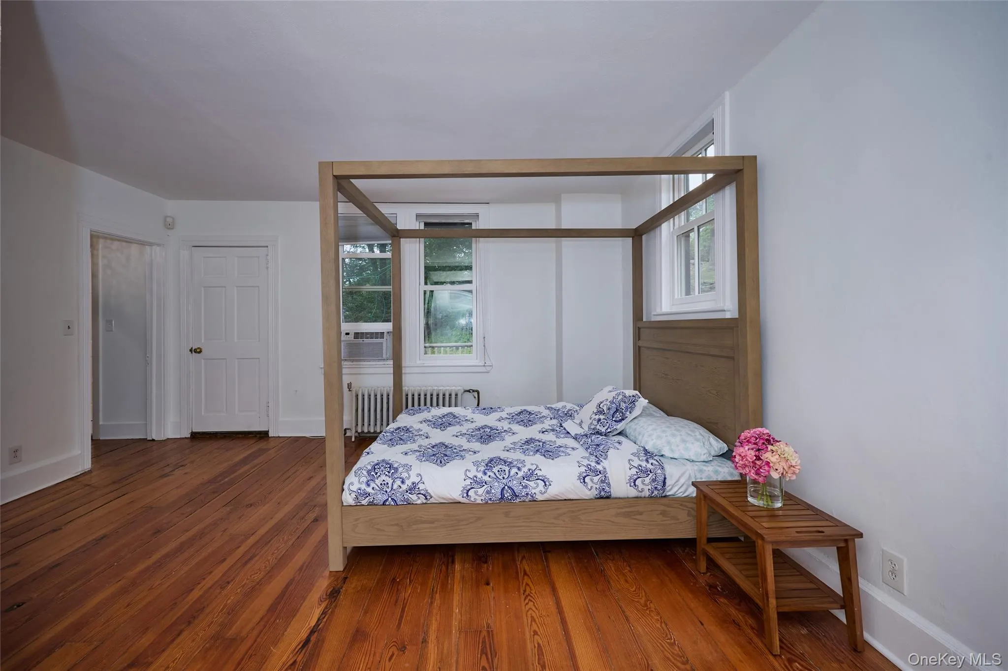 Bedroom with wood finished floors and radiator heating unit Bedroom with wood finished floors and radiator heating unit