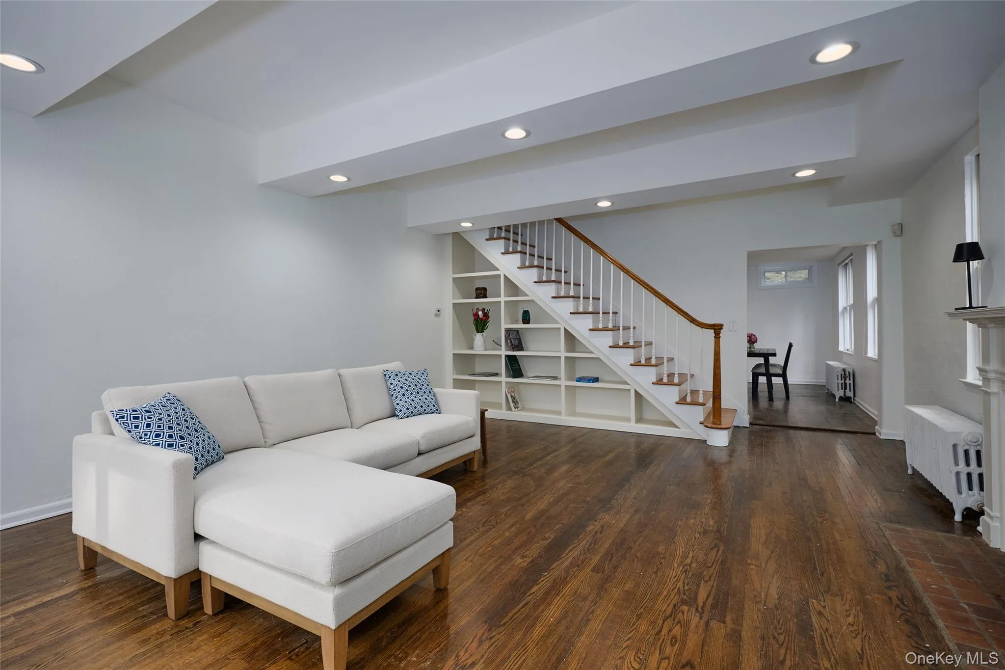 Living room with recessed lighting, radiator heating unit, dark wood finished floors, and stairs Living room with recessed lighting, radiator heating unit, dark wood finished floors, and stairs