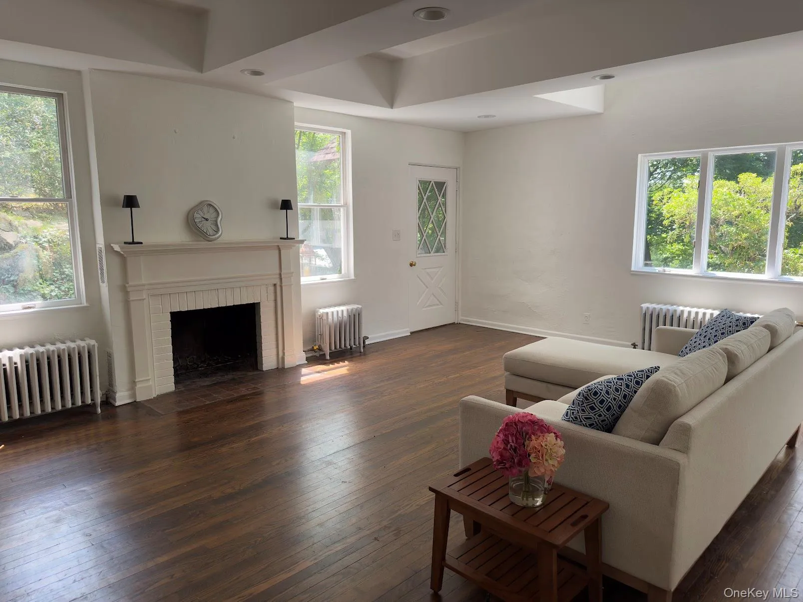 Living area featuring dark wood finished floors, radiator, and a fireplace Living area featuring dark wood finished floors, radiator, and a fireplace