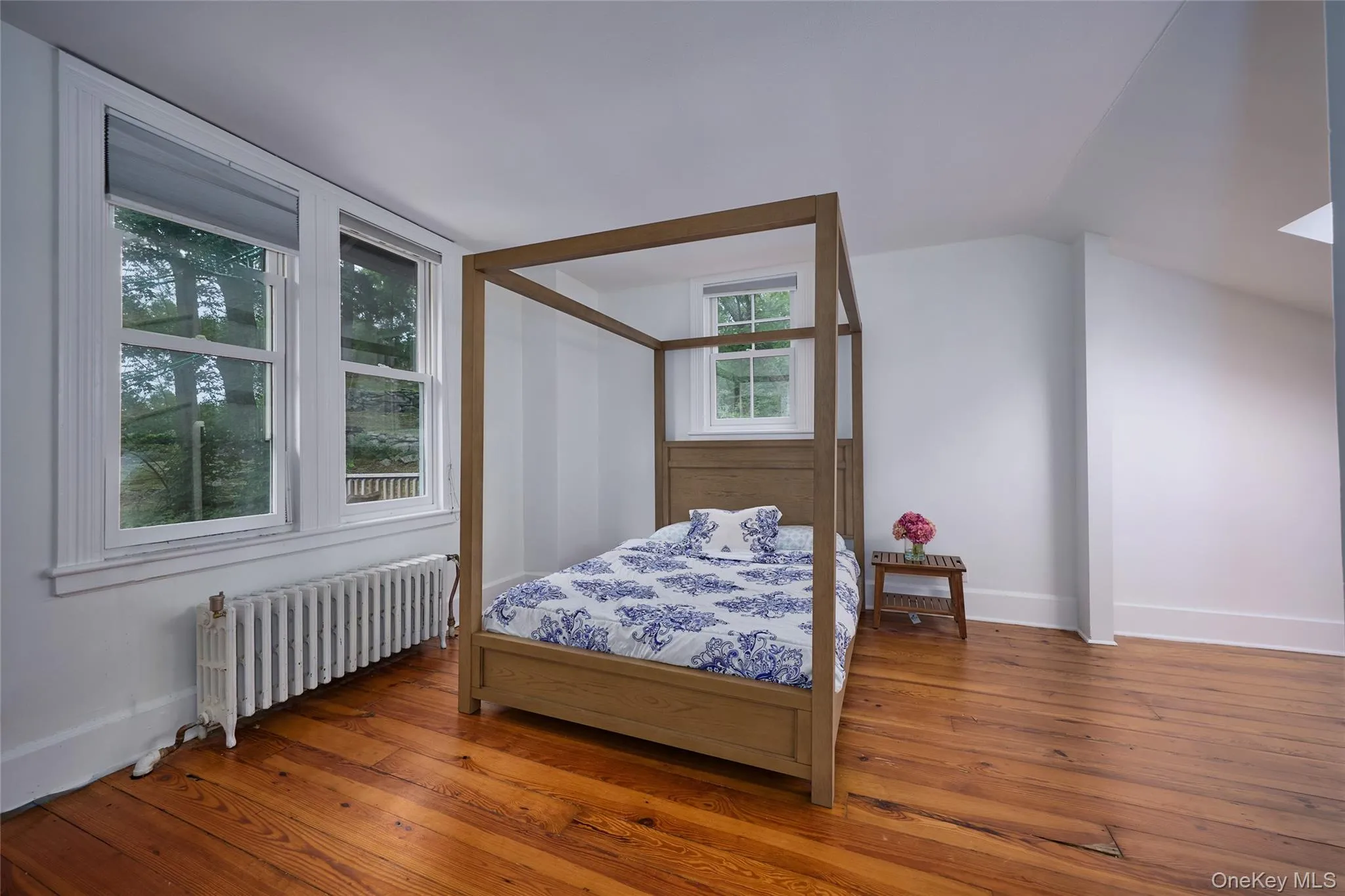 Bedroom featuring radiator heating unit and hardwood / wood-style floors Bedroom featuring radiator heating unit and hardwood / wood-style floors