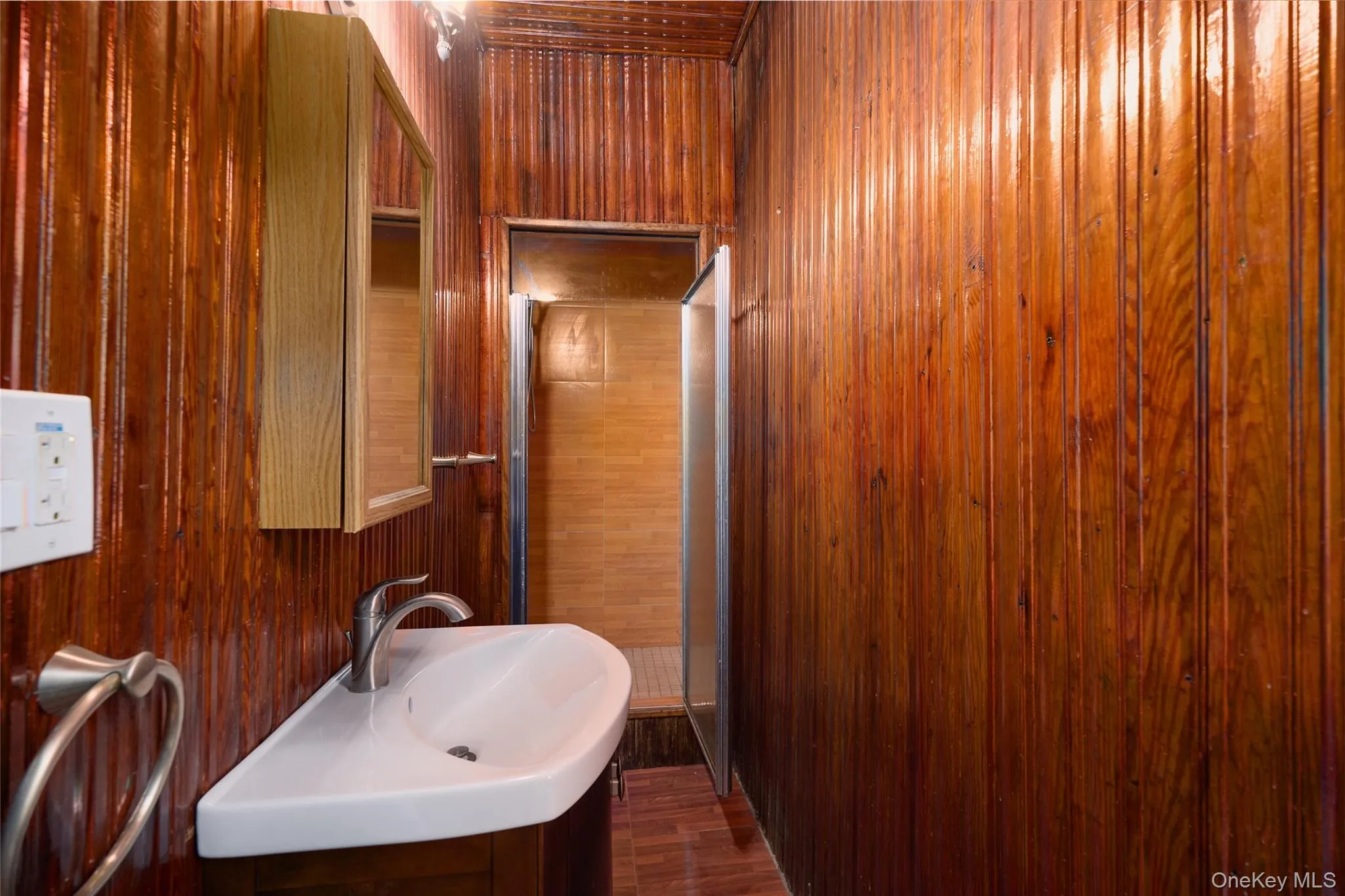 Bathroom featuring vanity, wooden walls, and dark wood finished floors Bathroom featuring vanity, wooden walls, and dark wood finished floors