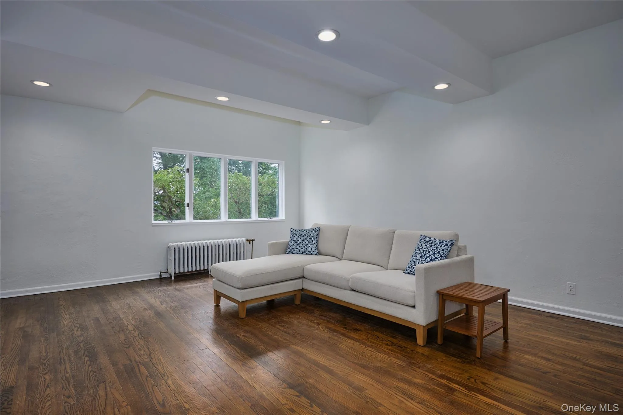 Living area featuring radiator heating unit, dark wood-style floors, and recessed lighting Living area featuring radiator heating unit, dark wood-style floors, and recessed lighting
