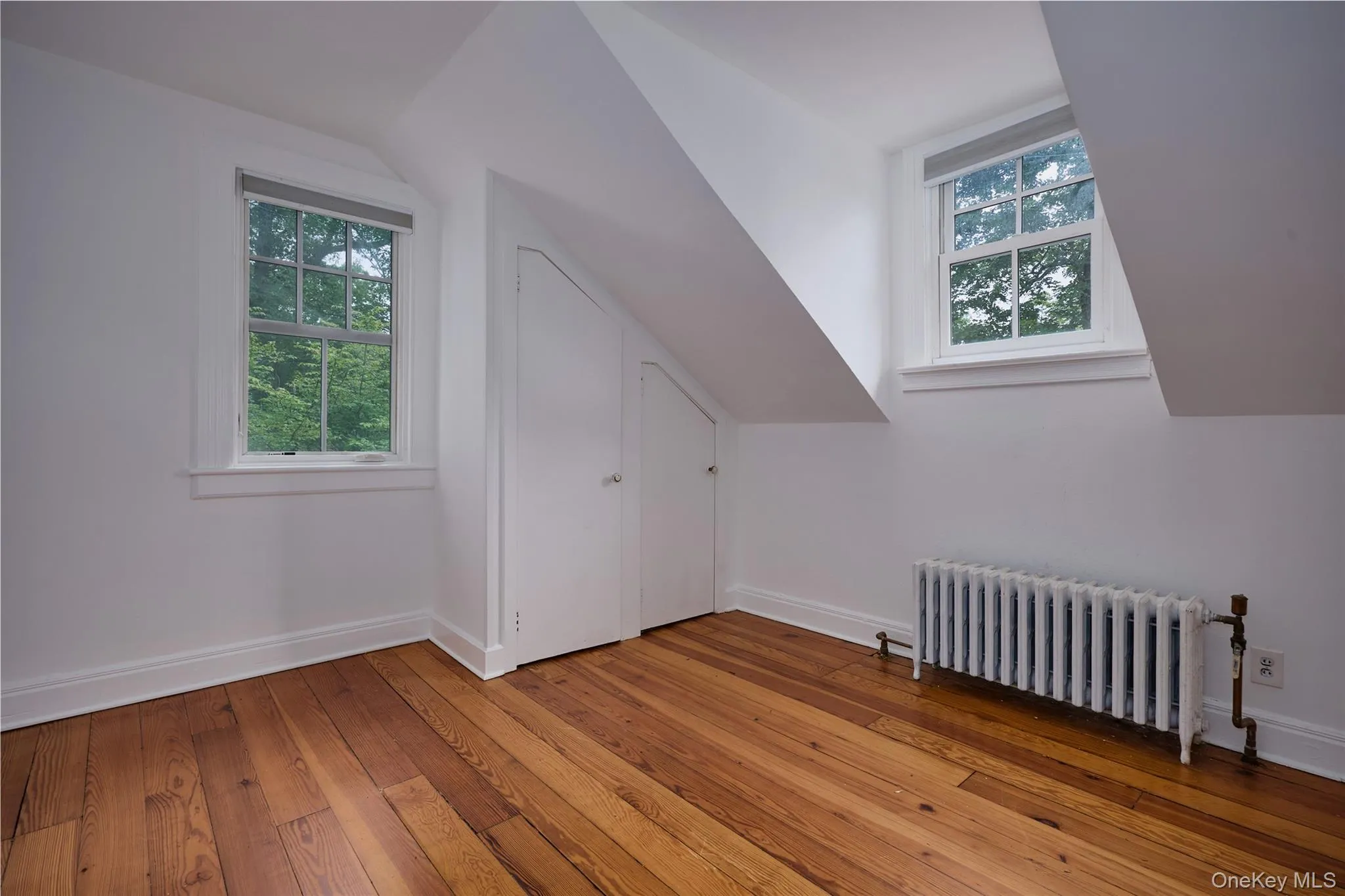 Bonus room featuring radiator heating unit, hardwood / wood-style flooring, and vaulted ceiling Bonus room featuring radiator heating unit, hardwood / wood-style flooring, and vaulted ceiling